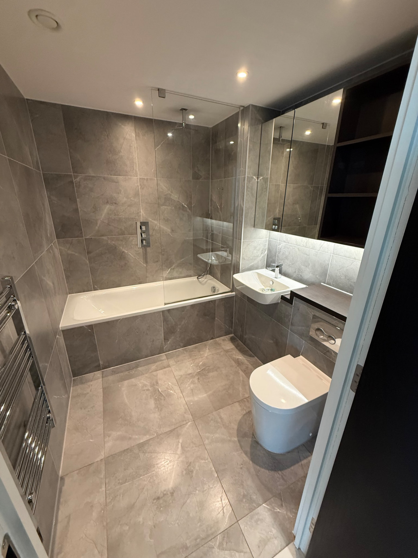Bathroom with a bath, glass screen, basin and tiled floor